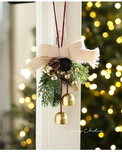 Close-up of beige linen bow with natural pine cones and gold bells on Christmas tree