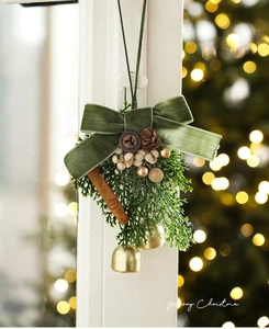 Detail of Christmas ornament with velvet bow, pine cones, and small gold bells hanging