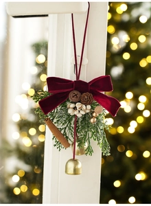 Christmas hanging decor with velvet bow, pine cones, and gold bells on a window frame