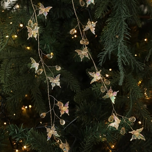 Iridescent butterfly garland with pearl beads hanging on a lush green Christmas tree