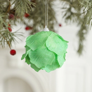 Sparkling green foam Christmas ball with petal texture hanging on a holiday tree