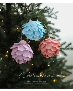 Detalle de adornos navideños de fieltro en forma de piña colgados en el árbol