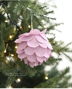 Primer plano de adorno navideño de fieltro rosa con forma de piña colgado en el árbol