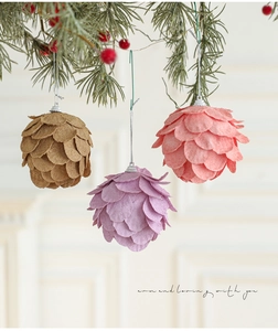 Primer plano de adornos de fieltro con forma de piña en marrón, morado y rosa en el árbol