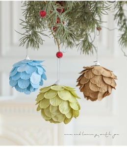 Detalle de adornos navideños en forma de piña con pétalos de purpurina y bayas