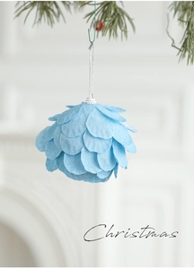 Detalle de bola de Navidad azul claro con textura de pétalos colgada en el pino