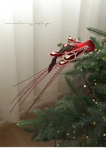 Macro shot of red glitter Christmas bird ornament with rhinestones and feathers on tree