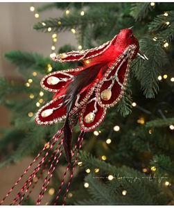 Detailed view of red artificial bird ornament with glitter and feathers on Christmas tree