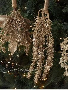 Detail von champagnergoldenen Glitzerzweigen am Weihnachtsbaum mit warmen Lichtern