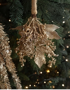Nahaufnahme eines champagnergoldenen Glitzerzweigs an einem Weihnachtsbaum mit Lichtern