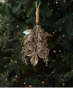 Detail eines champagnergoldenen Glitzerblatt-Anhängers an einem weihnachtlichen Tannenzweig