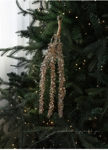 Detail von champagnerfarbenem Glitzer-Zweig mit Hanfseil an einem grünen Weihnachtsbaum