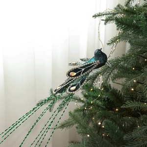 Sparkling green bird ornament with glitter and gems on a lighted Christmas tree