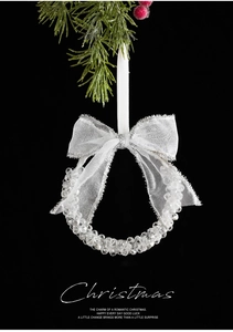 Detail of beaded crystal Christmas wreath ornament with white bow on pine branch