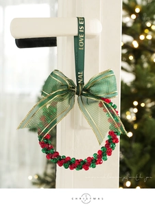 Detail of red and green beaded Christmas wreath ornament on a white door handle