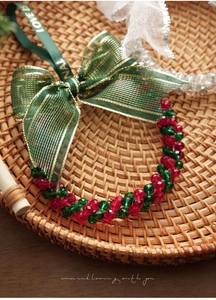 Detailed view of Christmas crystal bracelet with red and green beads and a green ribbon bow