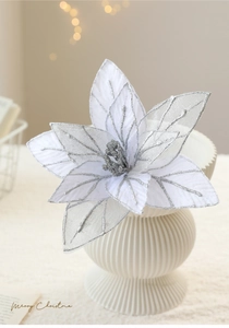 White and silver glitter artificial poinsettia flower in a white ceramic vase decoration