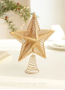 Macro view of gold wire woven Christmas tree star topper with beaded edges and spring base