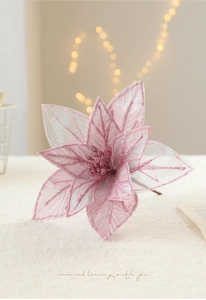 Pink artificial Christmas poinsettia with glitter detail on warm bokeh background