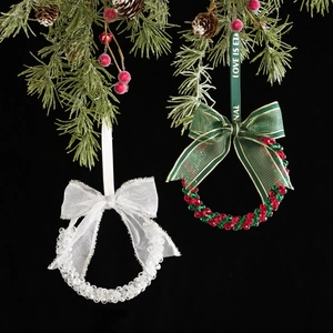 Elegant beaded Christmas bell ornaments with ribbon bows hanging from festive pine branches
