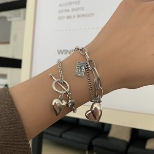 Close-up of retro silver heart bracelet set with T-bar clasp and engraved metal tag