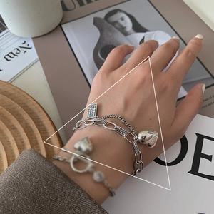 Close-up of vintage silver layered bracelet with heart charms and engraved nameplate tag