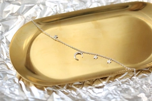 Macro shot of silver S925 sterling silver chain with moon and star pendants on tray