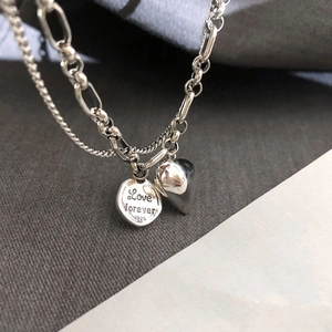 Macro detail of S925 silver double layer necklace with heart and Love forever disk charms
