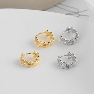 Macro detail of gold and silver laurel leaf earrings featuring tiny inset crystals