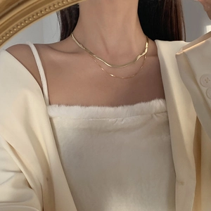 Primo piano di una collana a doppio strato dorata a serpente per un look a strati raffinato