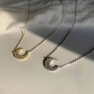 Détail de pendentifs lune avec nacre et zircons sur chaînes dorées et argentées