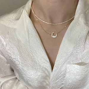 Détail d'un collier double épaisseur en argent avec pendentif lune en nacre et zircons