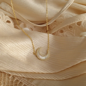 Collier lune en argent avec incrustation de nacre et zircons sur fond de dentelle beige