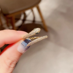 Detailed close-up of a dual-headed snake ring with white zircons and green eyes
