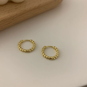 Classic golden twisted rope hoop earrings in 925 sterling silver on minimalist background