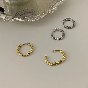 Minimalist 925 silver twisted hoop earrings in gold and silver finishes on beige surface