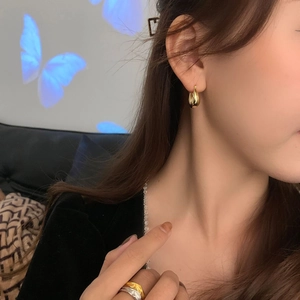 Detailed view of polished gold teardrop hoop earring on model with creative lighting