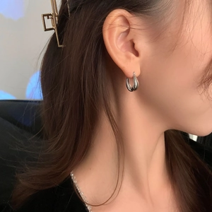 Close-up of minimalist teardrop earrings with polished silver finish on a female model