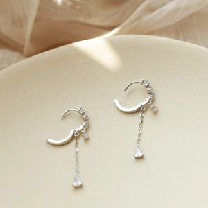 Detailed close-up of silver drop earrings with long chains and sparkling zircon stones