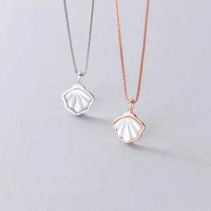 Detail of shell-shaped pendants in silver and rose gold with white mother of pearl inlay