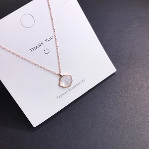 Detail of rose gold shell pendant necklace on display card with polished finish