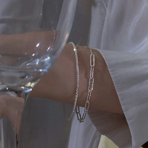 Close-up of double-layer silver sparkling star chain and paperclip bracelet on wrist