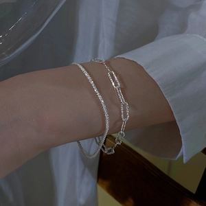 Close-up of sparkling double-layer silver bracelets on model wrist with minimalist style