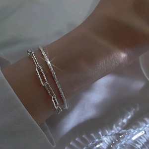 Close-up of double-layer silver bracelets with star-like shimmering and paperclip chain