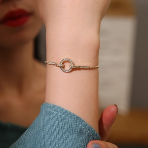 Dettaglio macro di un bracciale regolabile in oro con anello cavo e zirconi incastonati
