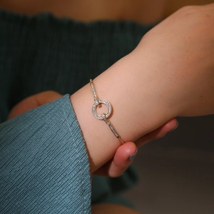 Dettaglio del bracciale dorato regolabile con anelli intrecciati e pavé di zirconi