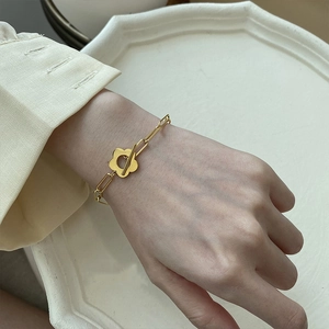Gold plated metal chain bracelet with floral OT buckle fastener shown on wrist