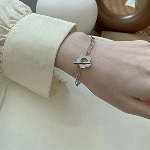 Silver paperclip chain bracelet with hollow flower charm and toggle clasp on wrist