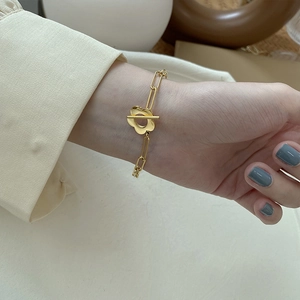 Detail of gold-plated chain bracelet with floral toggle clasp on model wrist