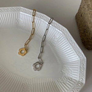 Detailed macro view of gold and silver plated chain bracelets with floral charms in a tray